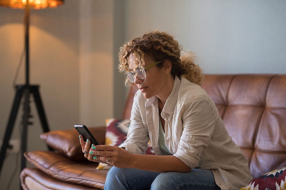 Woman sitting on sofa with phone in hand